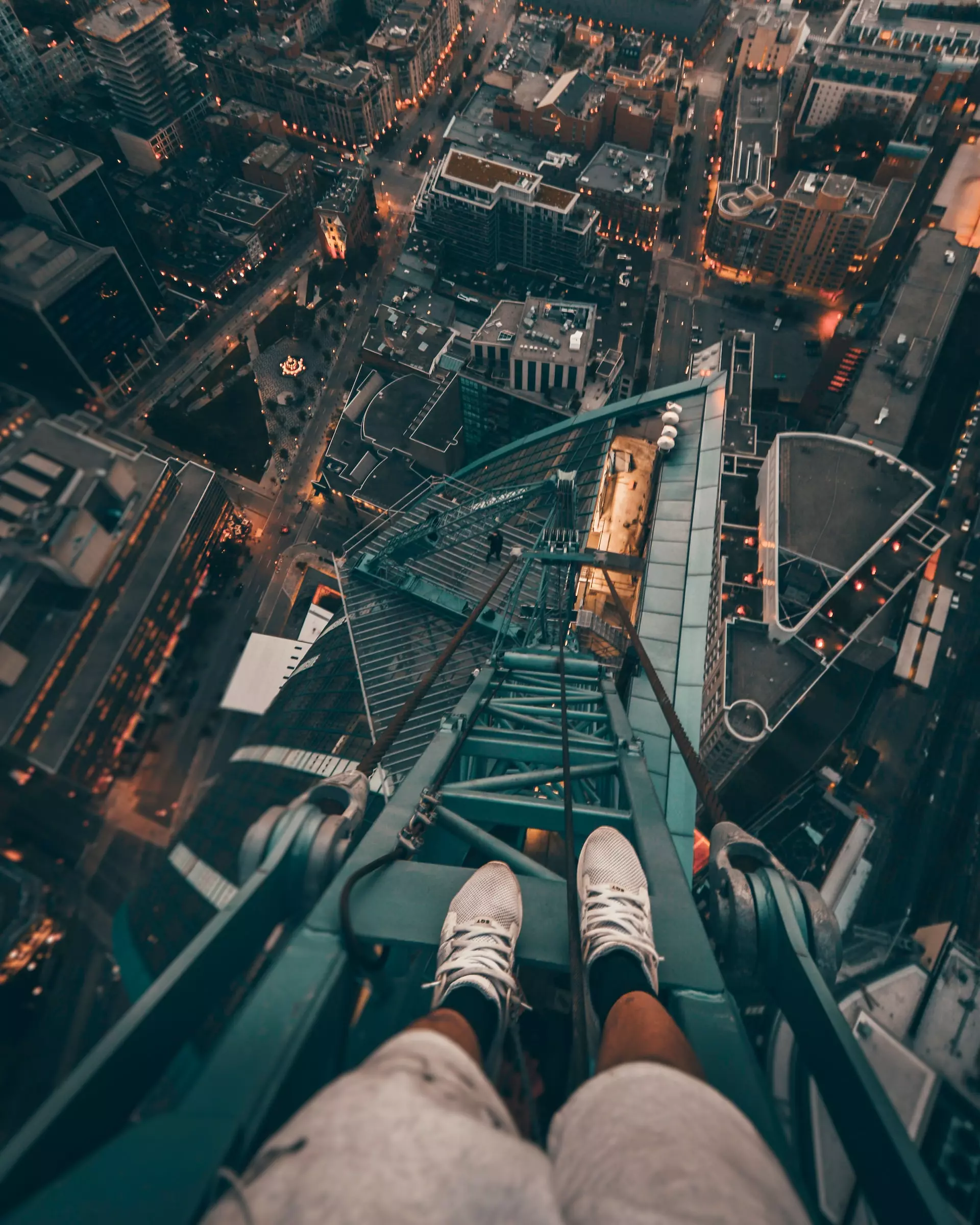 View from perspective of a free climber atop a crane looking down onto a cityscape