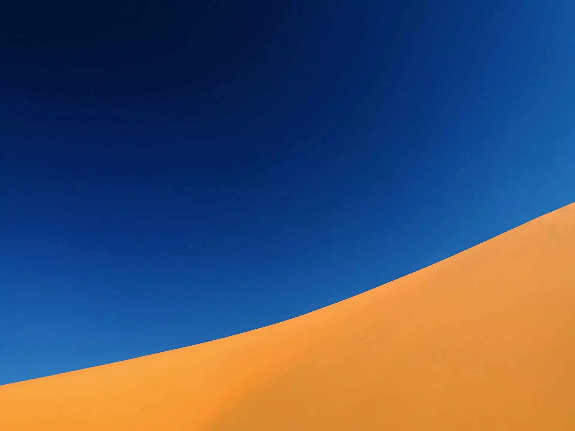 The slope of a sand dune against deep blue sky