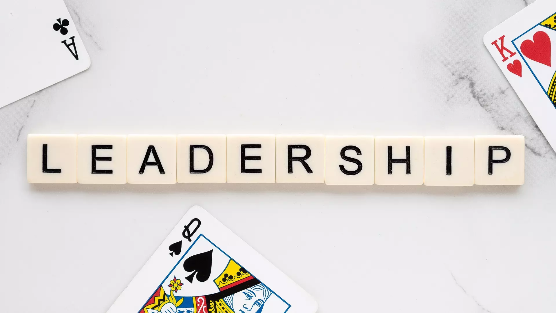 The word 'Leadership' spelled out in Scrabble tiles and surrounded by playing cards