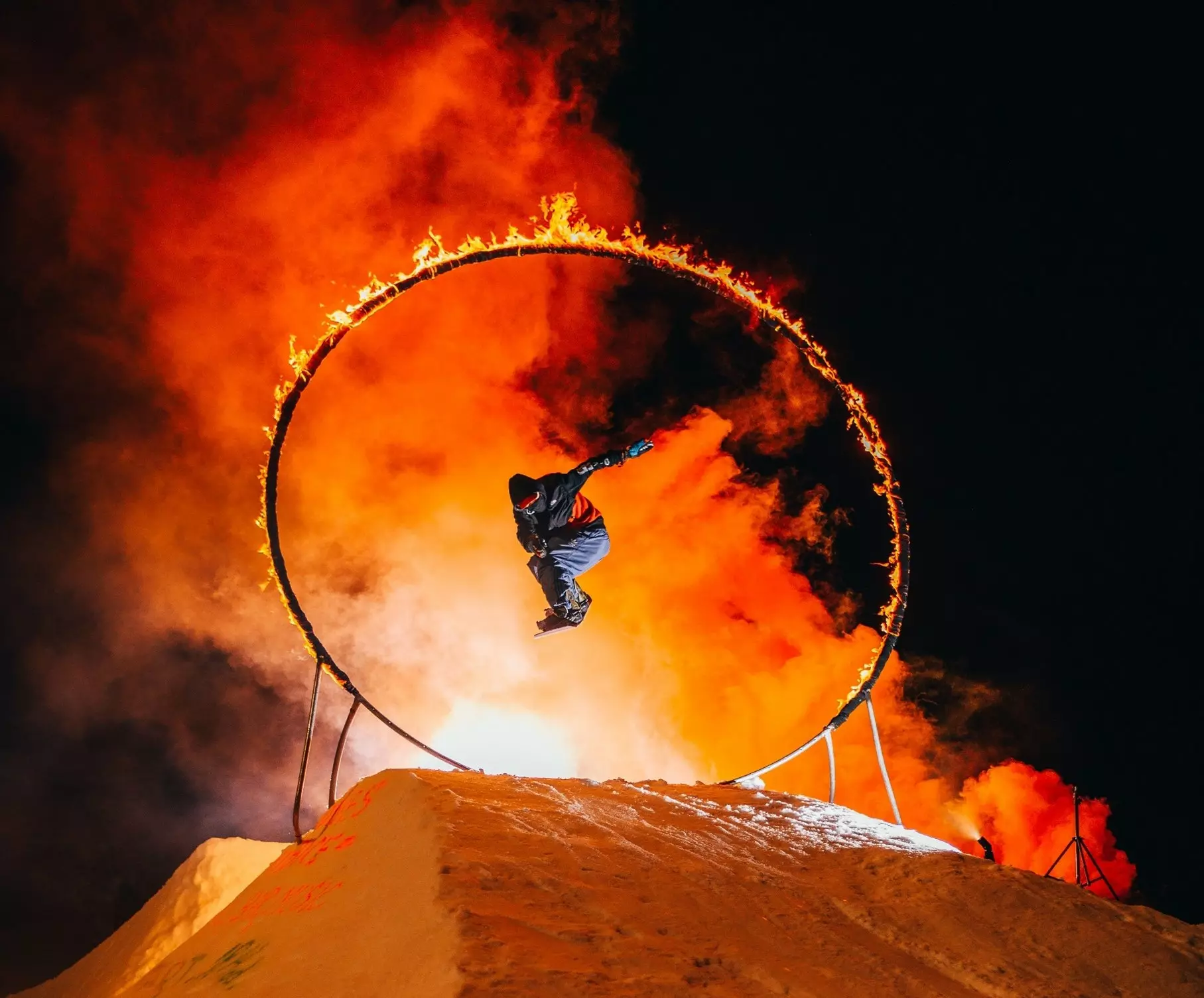 Snow boarder jumping through a flaming hoop