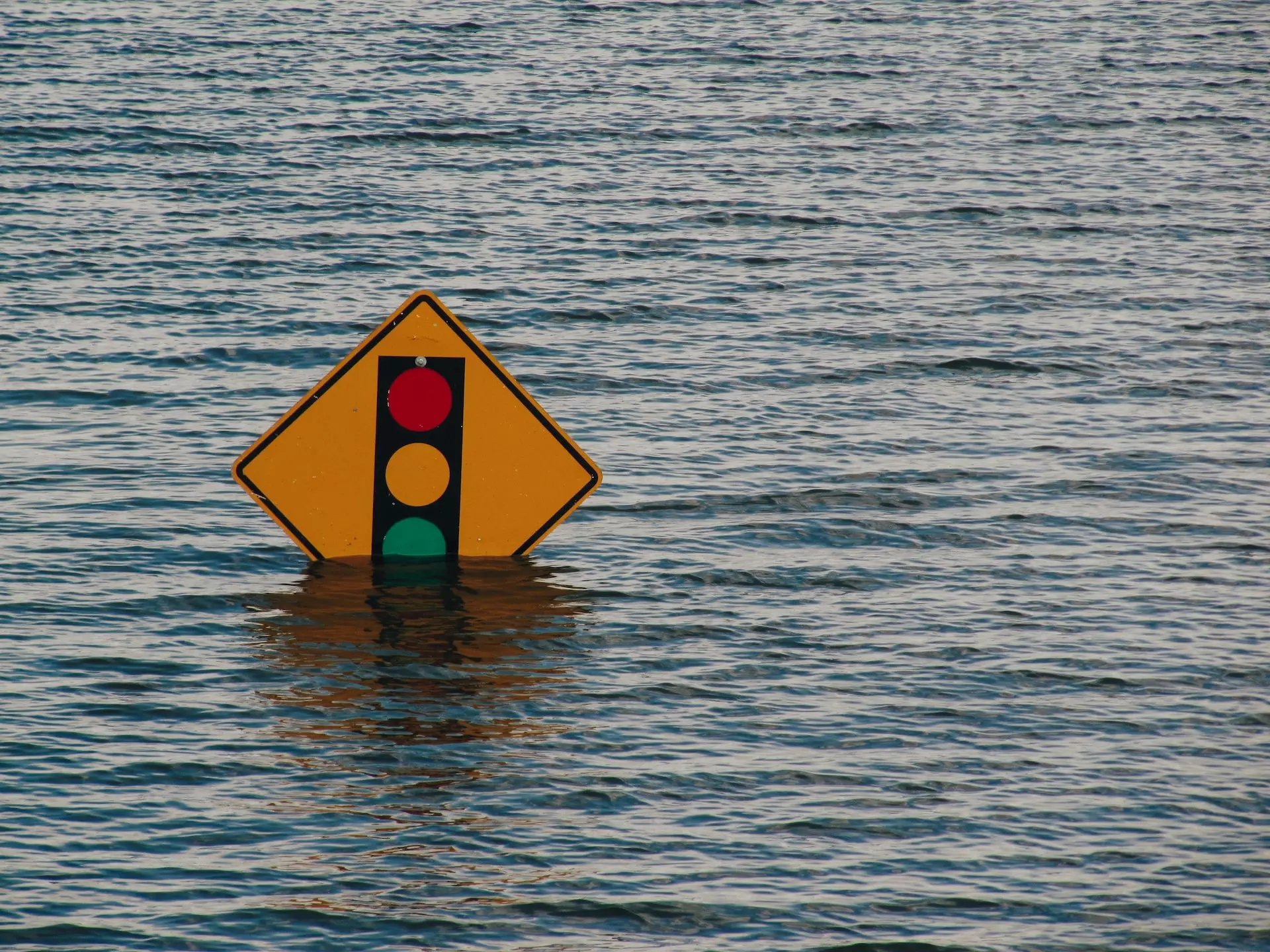 A traffic light sign partially submerged by flood water