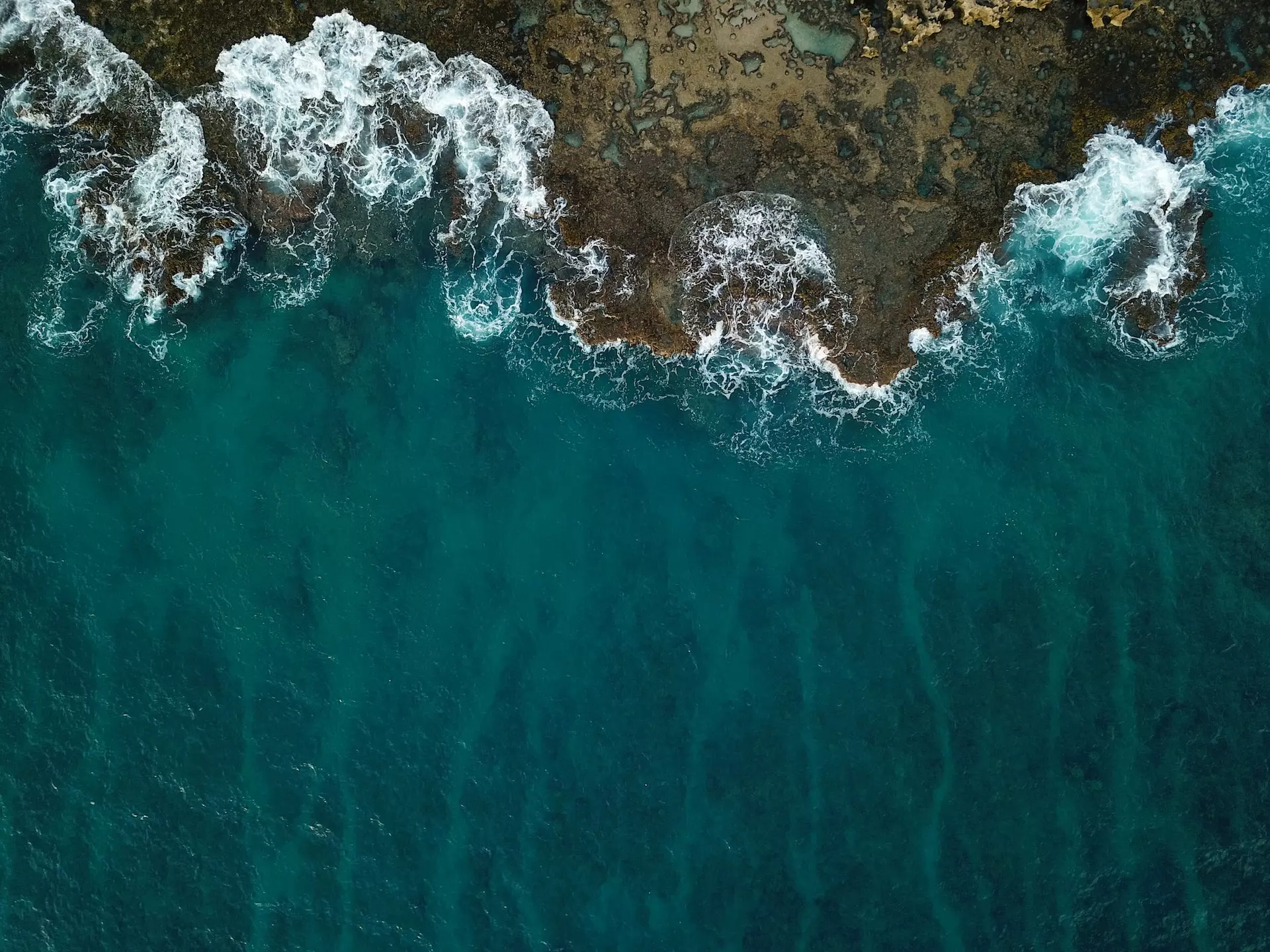 Aerial view of sea waves meeting a rocky coast