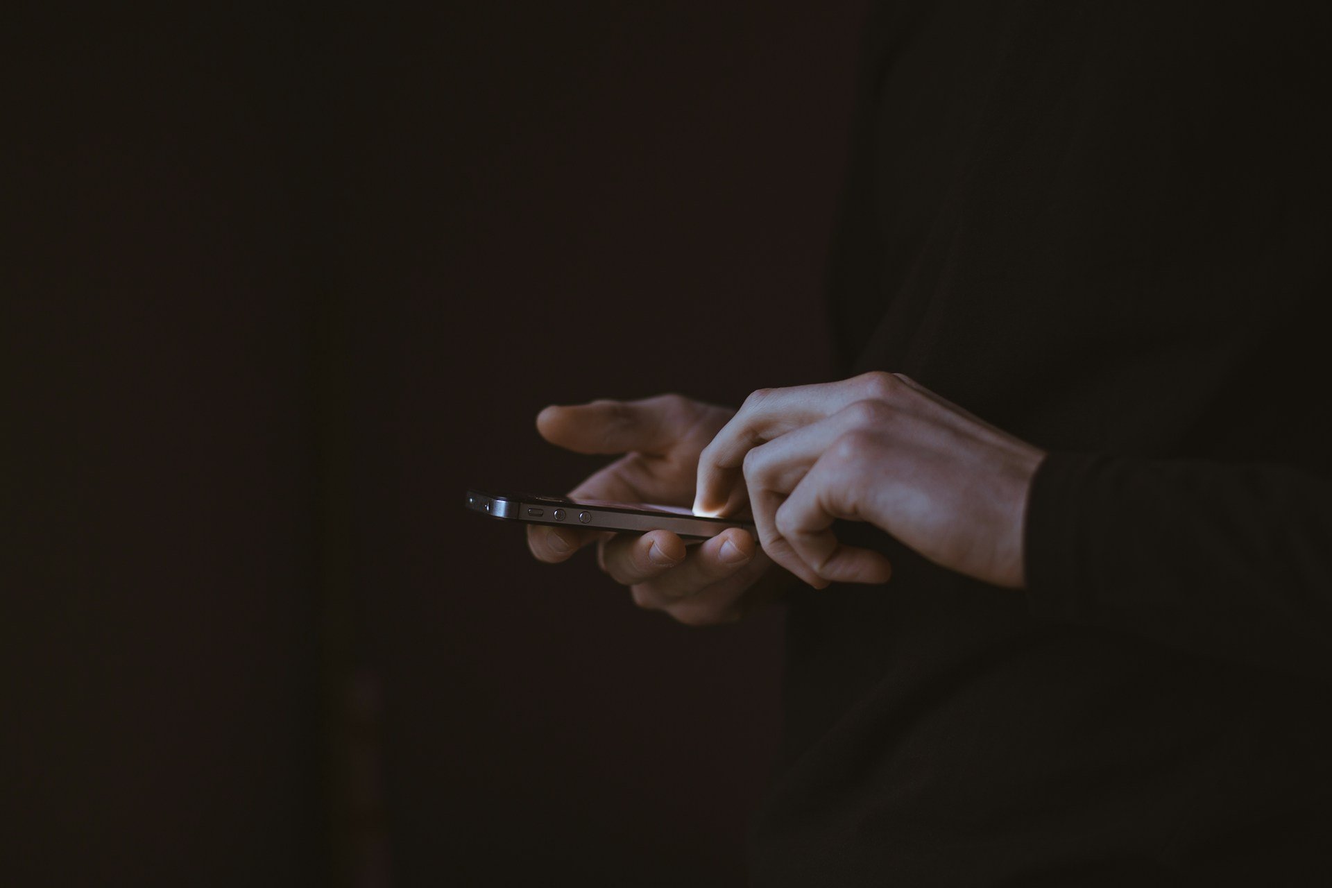 Silhouette of a person's hands using a smart phone
